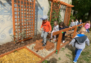 dzieci idą po ścieżce edukacyjnej na terenie ogródka "Słoneczna Akademia"
